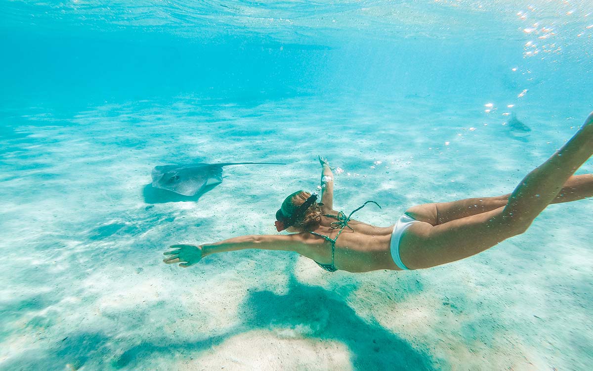 Woman snorkeling with a sting ray in Tahiti